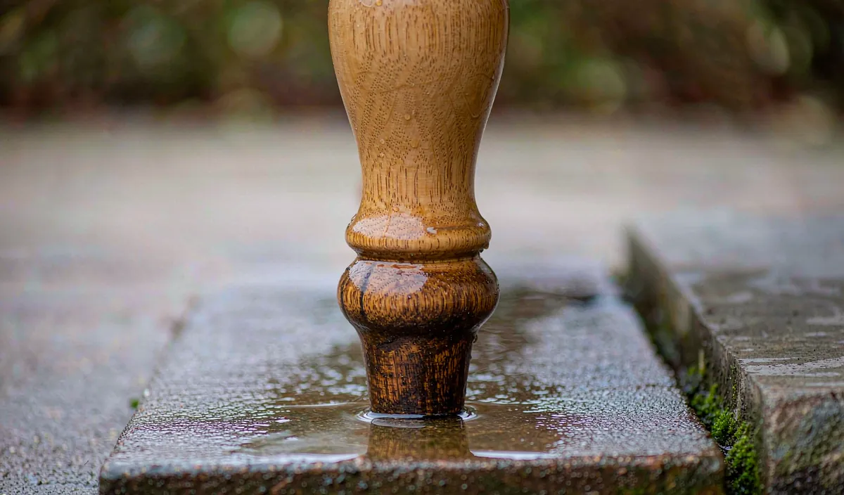 The bottom of a bench leg on a wet paver, with water pooled around it