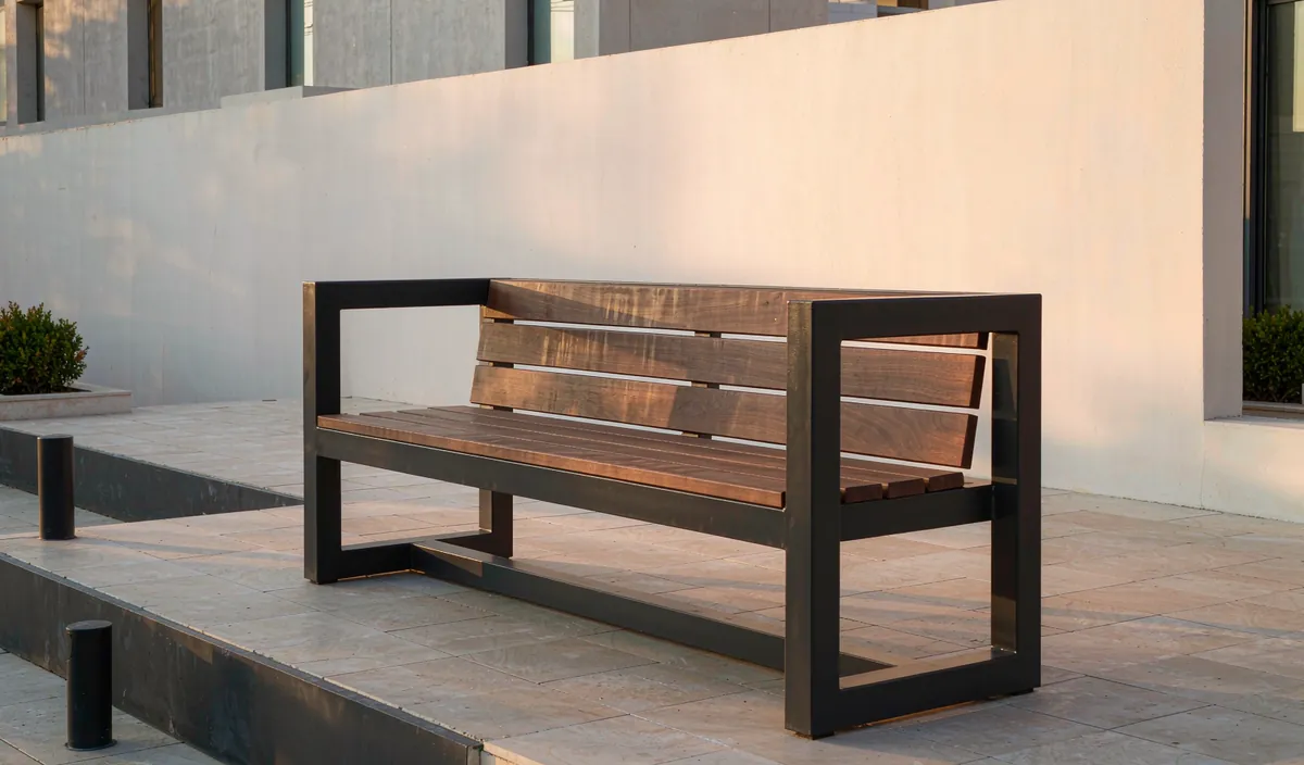 A modern outdoor bench with a black steel frame and wide wooden slats