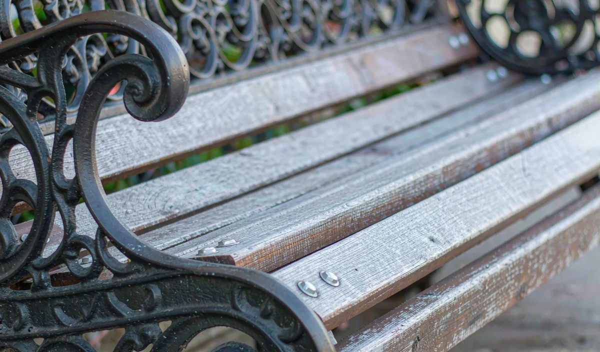 A close view of the cast iron end and wooden slats on a park bench