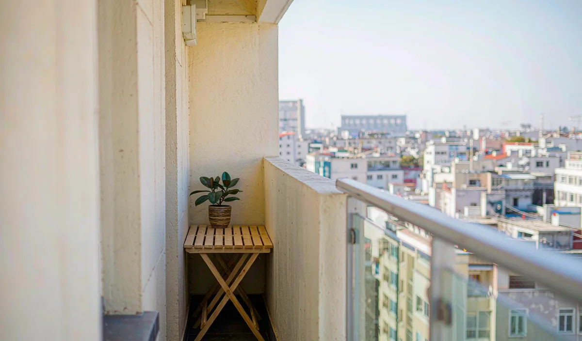 A small wooden bench tucked against the wall on a narrow apartment balcony