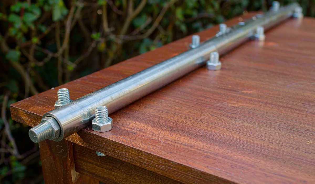 A long stainless steel hinge and galvanized bolts along the back edge of a storage bench lid